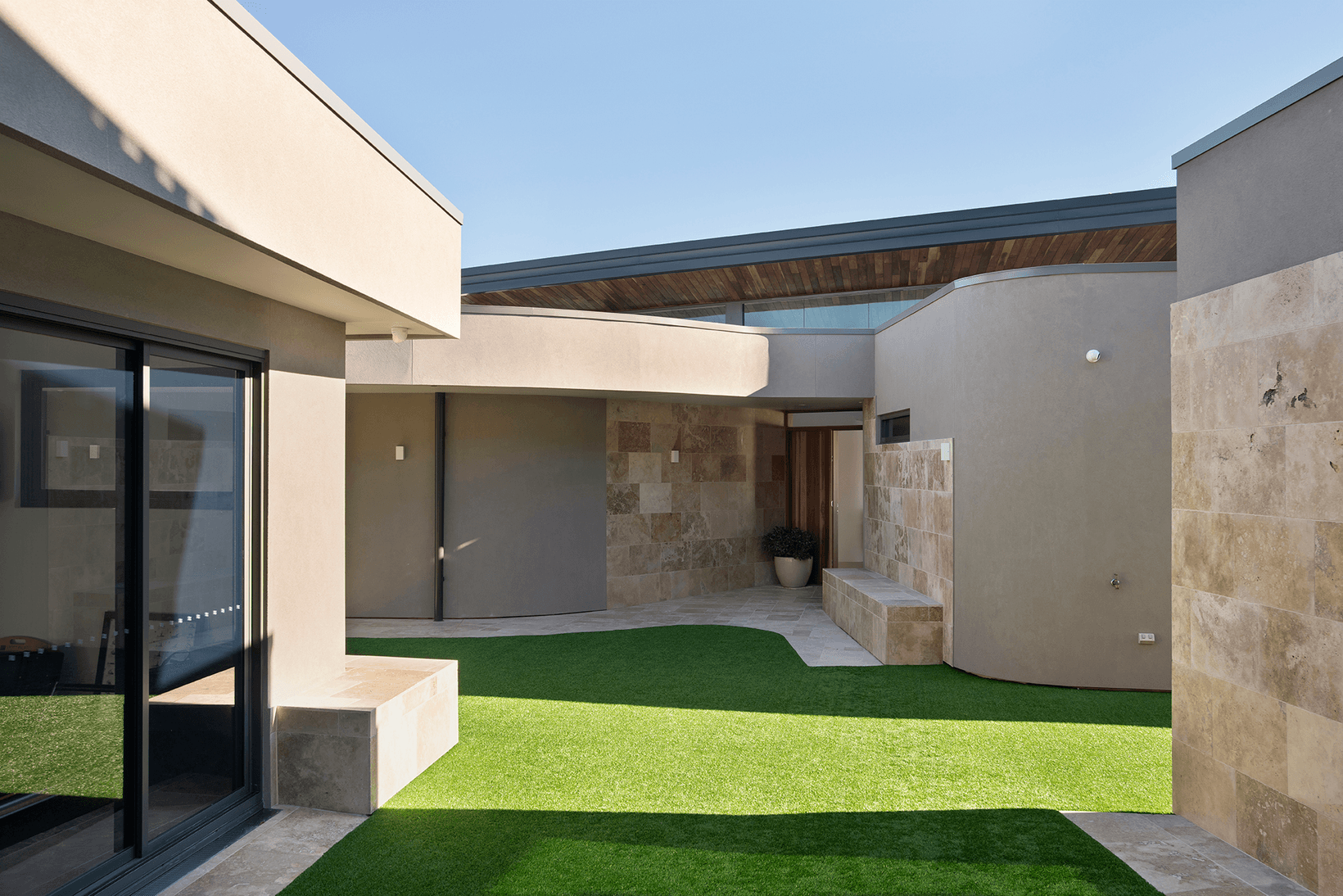 External curved walls made with Hebel showing open air courtyard with olive tree