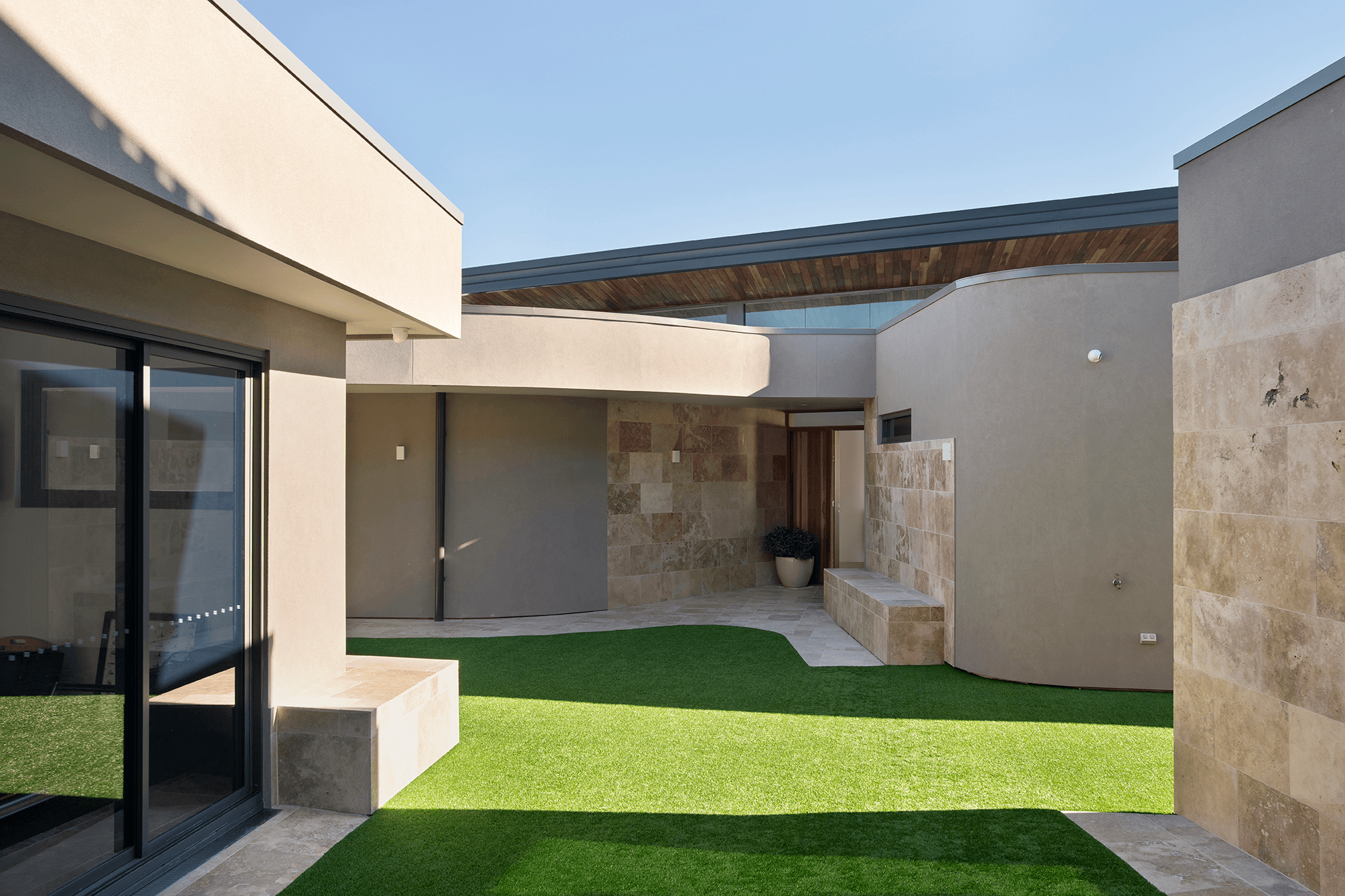 External curved walls made with Hebel showing open air courtyard with olive tree